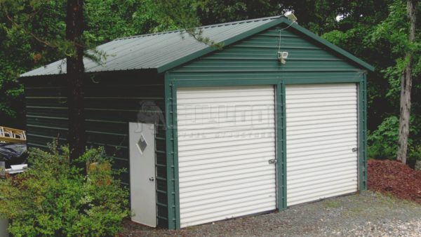 Green metal garage with 2 rolling white doors installed in South Carolina.