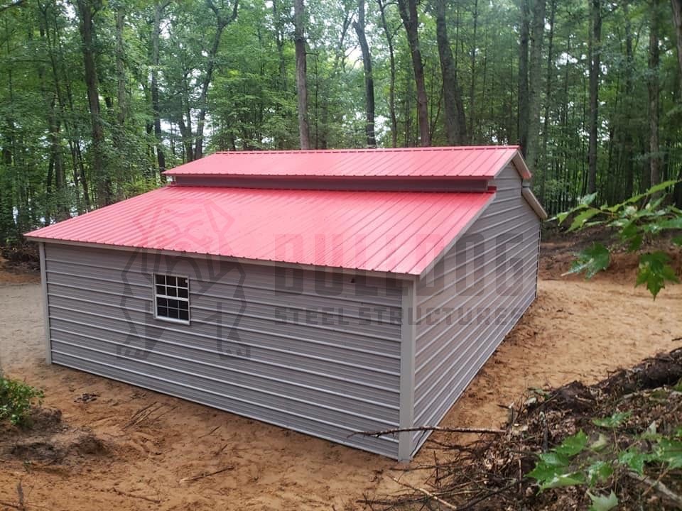 gray custom metal barn with a red roof